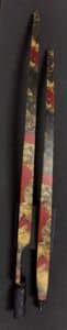 Two decorative sticks with red and gold patterns on a dark background.