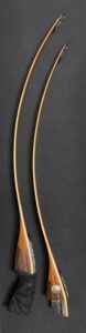 Close-up of two curved wooden sticks on a dark surface.