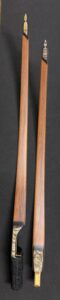 Two wooden sticks with a smooth finish on a black surface.