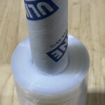 A roll of clear plastic wrap with a blue and white handle.