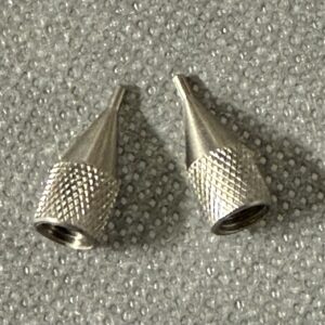 Two metal sewing thimbles on a textured surface.