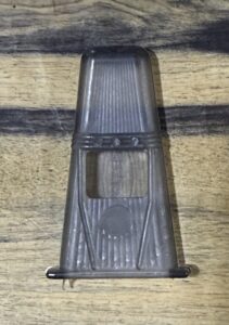 A vintage metal razor blade sharpener on a wooden surface.