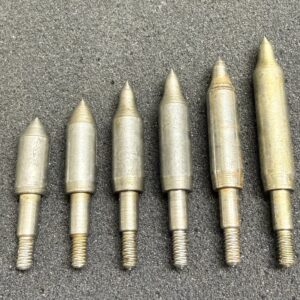 A set of six metallic pointed weights arranged by size on a grey surface.