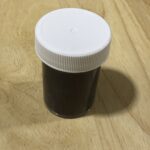 Small brown bottle with white cap on wooden surface.