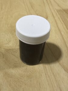 Small brown bottle with white cap on wooden surface.