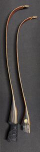 Two wooden knitting needles on a dark surface.