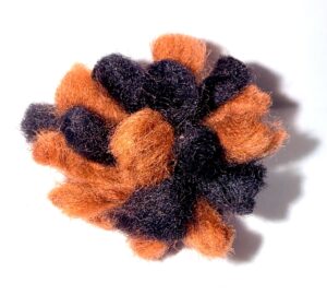 A fluffy pom-pom ball with orange and black colors.