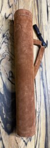 A close-up of a brown suede or velvet case with a strap on a blue and beige textured surface.