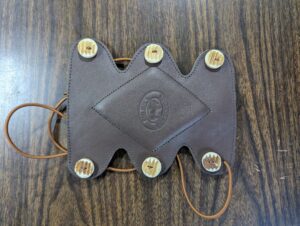 Vintage leather camera strap with brass buttons and embossed logo.