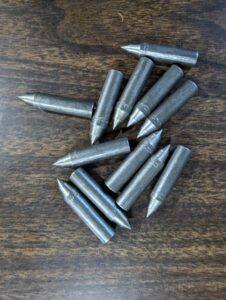 A pile of metallic rifle bullets on a wooden surface.