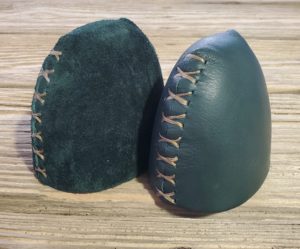 Two leather boxing hand wraps with laces on a wooden surface.