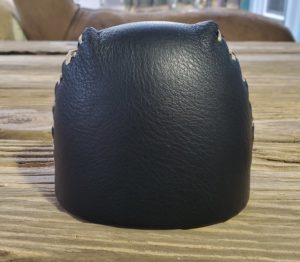 Black leather pouch with a drawstring on a wooden surface.
