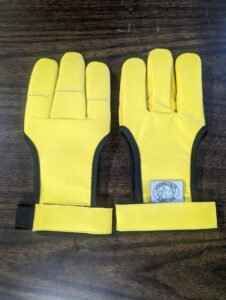 Pair of yellow gloves with unique finger design on a wooden surface.