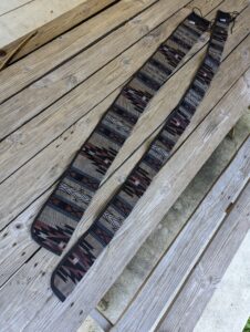 Pair of patterned skis laid on wooden deck.