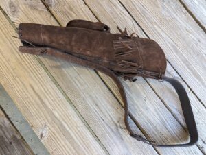 Brown leather crossbody bag on wooden floor.
