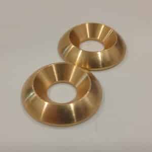 Two shiny brass conical rings with central holes on a plain surface.