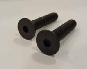 Two black hex socket flat head screws on a white surface.