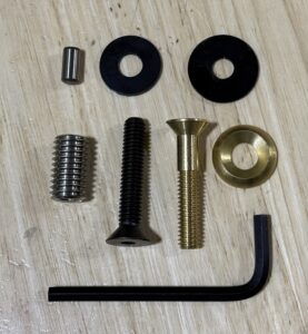 Various screws, bolts, nuts, and an Allen wrench on a wooden surface.