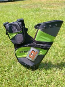 A black archery bow sight resting on grass.