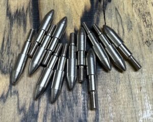 A collection of metallic bullet-shaped objects on a wooden surface.