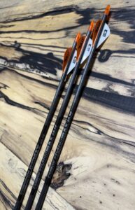 Three black and orange golf clubs resting on a wooden surface.