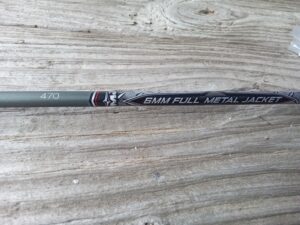 Close-up of a golf club shaft on a wooden surface.