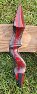 Close-up of a wooden object with intricate red and black swirling patterns.