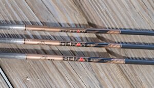 Three wooden baseball bats with 'BENAT' branding lying on a wooden surface.