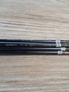 Three black pencils with white text on a wooden surface.