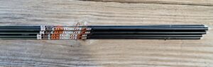 Three black graphite golf shafts labeled 'ELITE' on wooden surface.