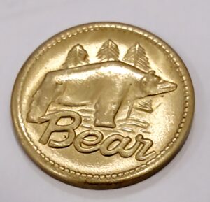 A gold coin featuring a bear and mountains with the word 'Bear'.