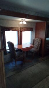 Cozy dining area with two cushioned chairs and a wooden table by large windows.