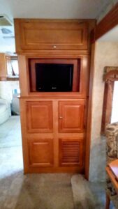 Wooden cabinet with a TV in an RV interior.