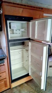 Open empty refrigerator with freezer on top and fridge below.