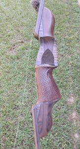 Close-up of a brown textured bow handle on grass.
