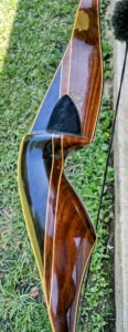 Close-up of a polished wooden archery bow with intricate grain and glossy finish.
