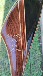 Close-up of a wooden bow with handwritten specifications.
