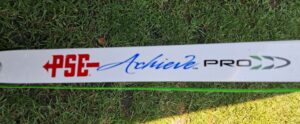 Close-up of a white sign with blue cursive text on grass.