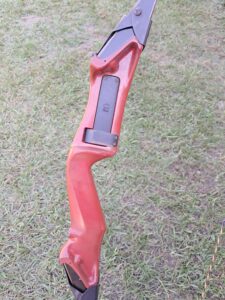 A wooden recurve bow resting on grass.