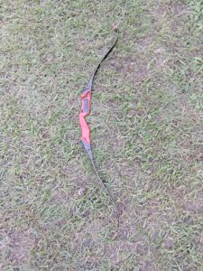 A traditional recurve bow lying on grass.