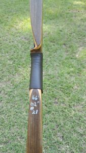 Close-up of a wooden recurve bow with markings on the limb.