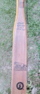 A vintage wooden cricket bat with visible grain and signatures on the blade.
