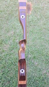 A polished wooden bow with a curved design on grass.