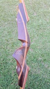 A wooden recurve bow standing on grass.