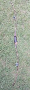 Traditional wooden bow lying on grass.