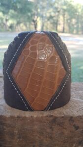 A close-up of a handcrafted leather pouch with a crocodile pattern.