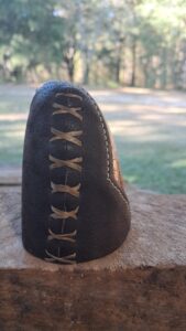 Close-up of a black leather pouch with decorative lacing on a wooden surface.