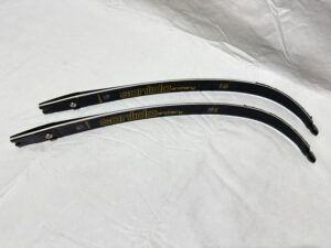 Two black hockey sticks with white markings on a white surface.