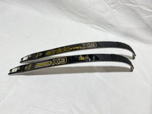 Three black and yellow hockey sticks on a white surface.