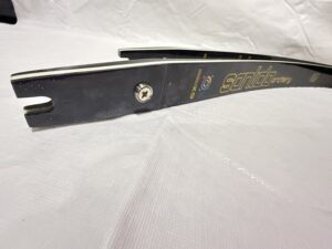 Close-up of a black archery bow limb with a metal bolt on a white surface.